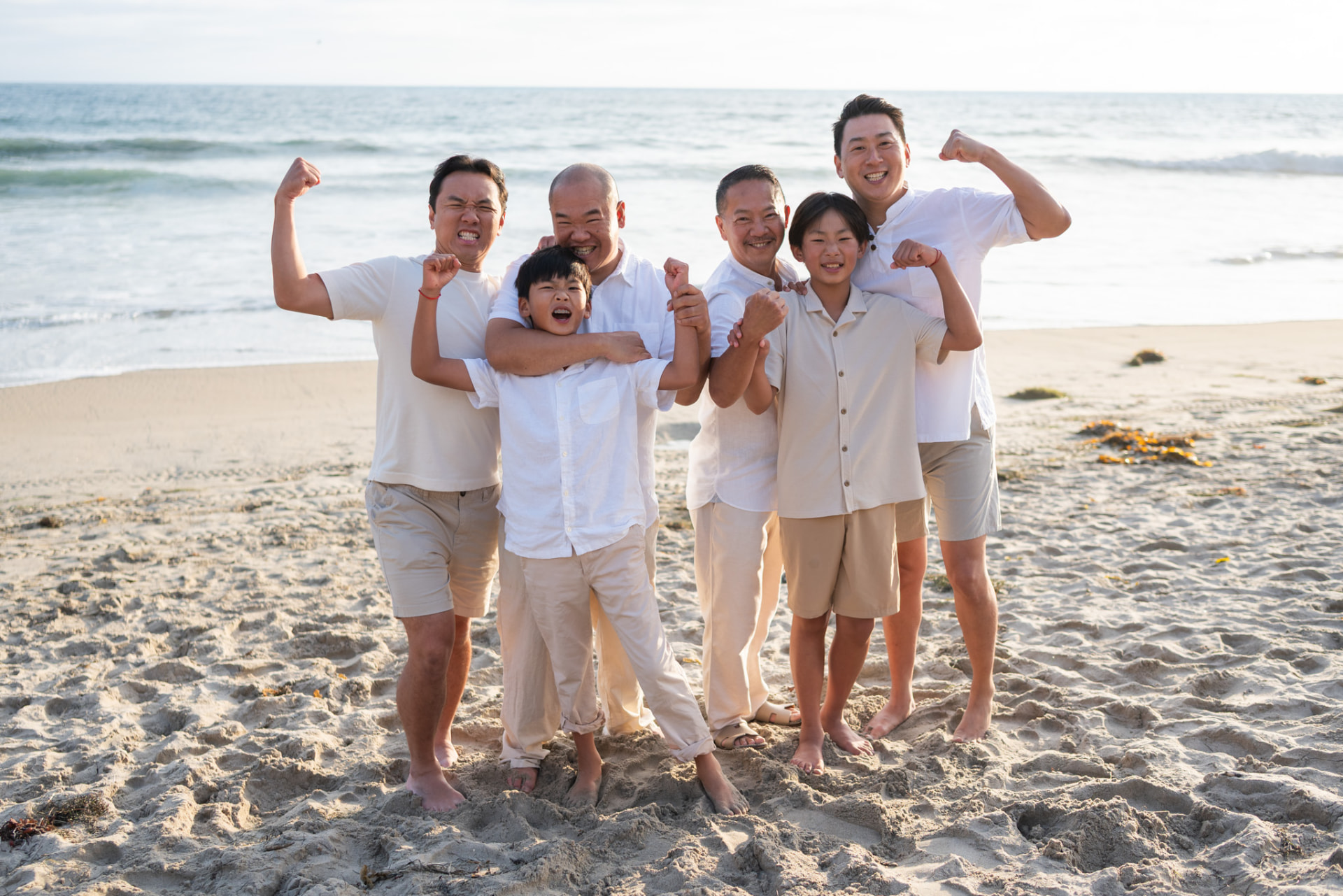 Dads and sons flexing and laughing on the beach