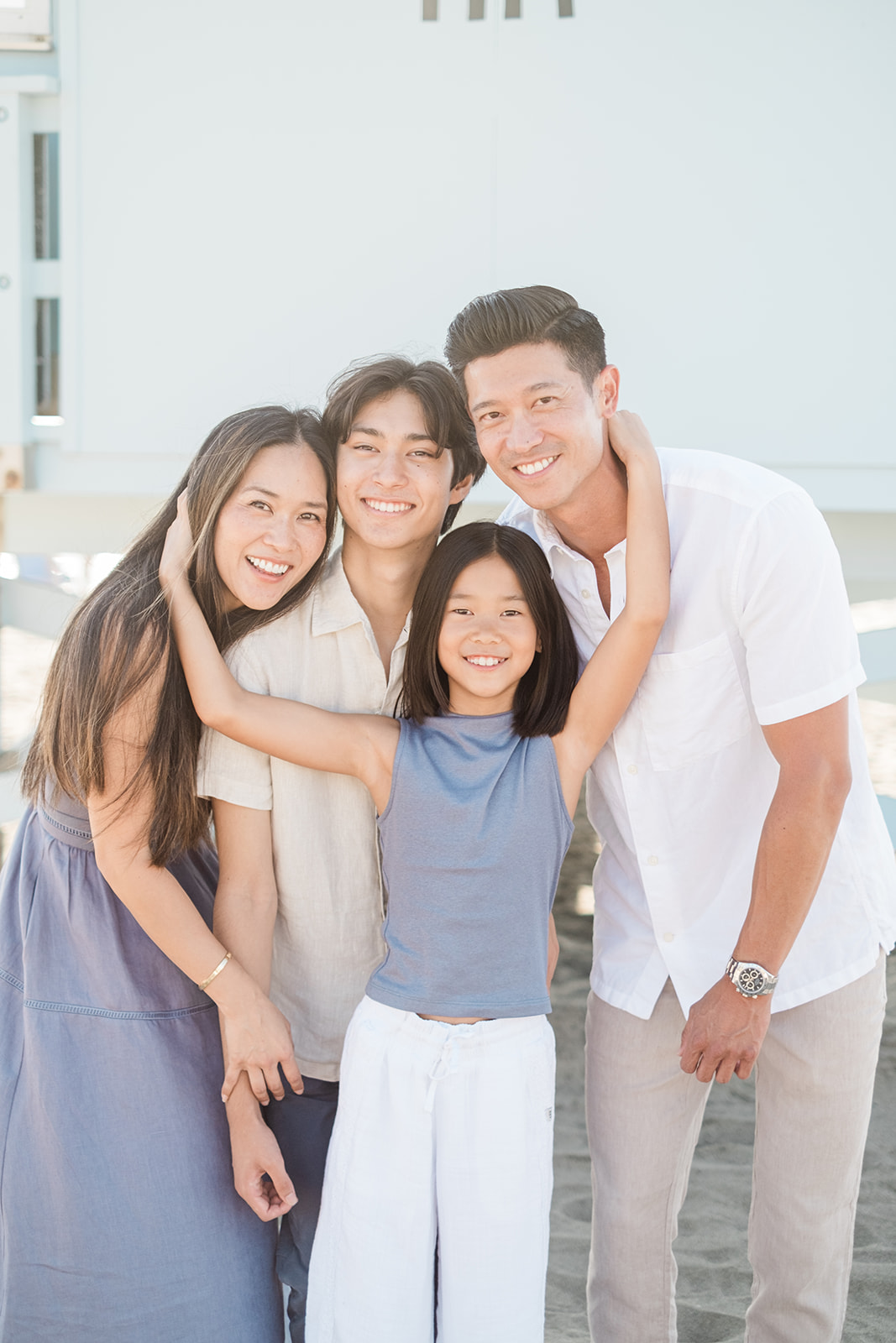 Family of four hugging close by the lifeguard tower