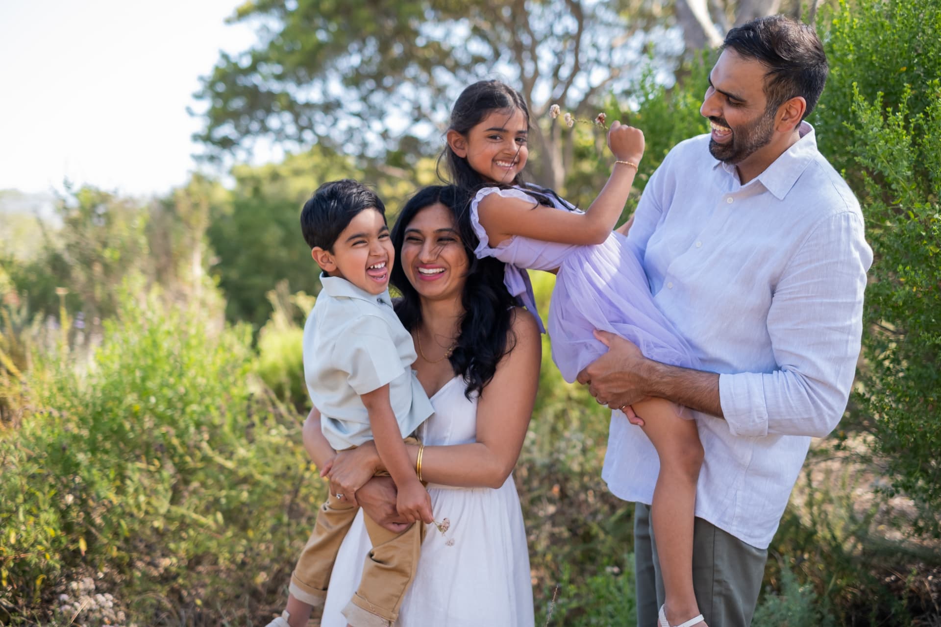Family laughing while carrying both kids in the garden