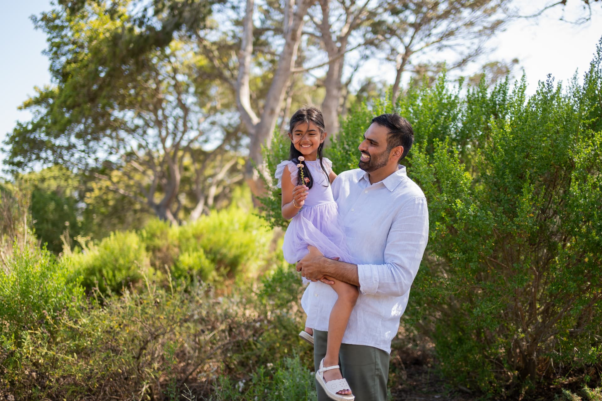 Dad carrying his daughter holding a wildflower