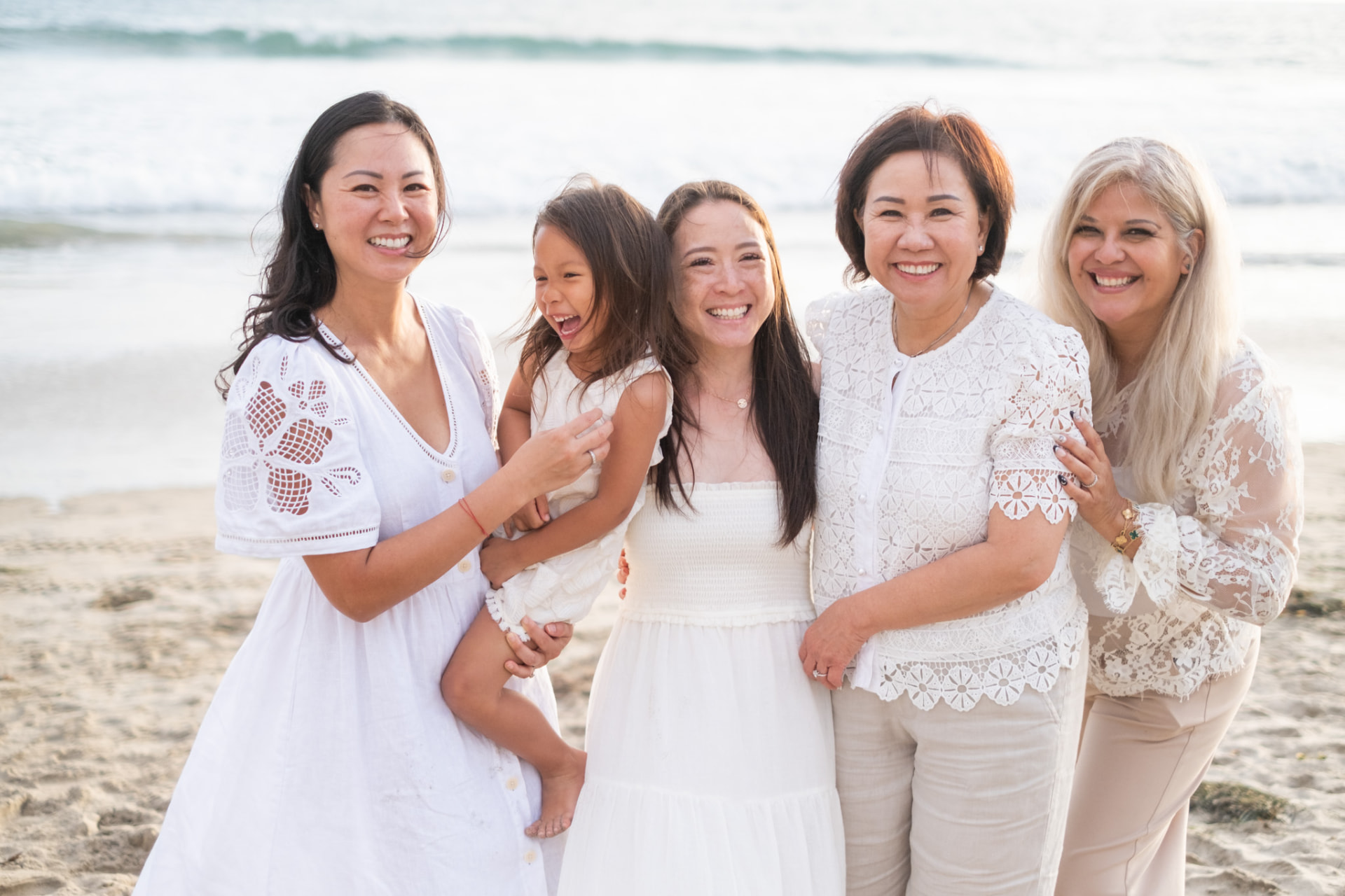 Generations of women laughing together on the shoreline