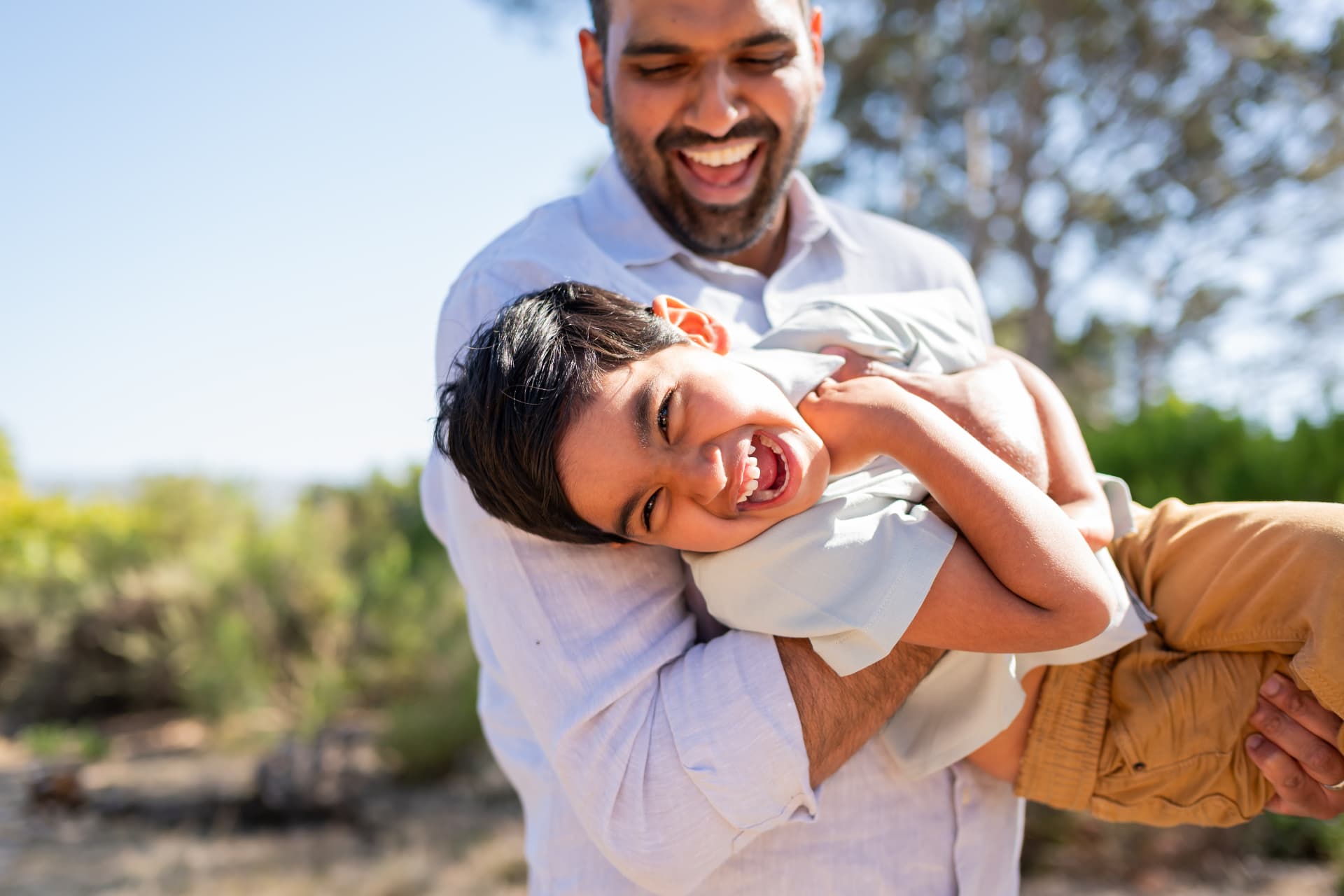 Dad laughing while cradling his giggling son