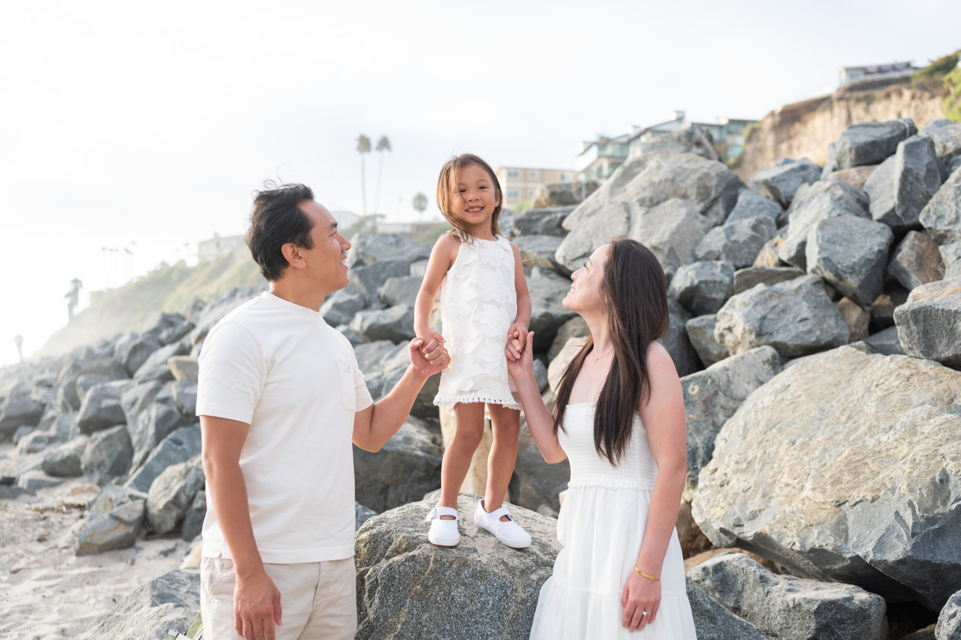 Parents holding their daughter's hands on the rocks