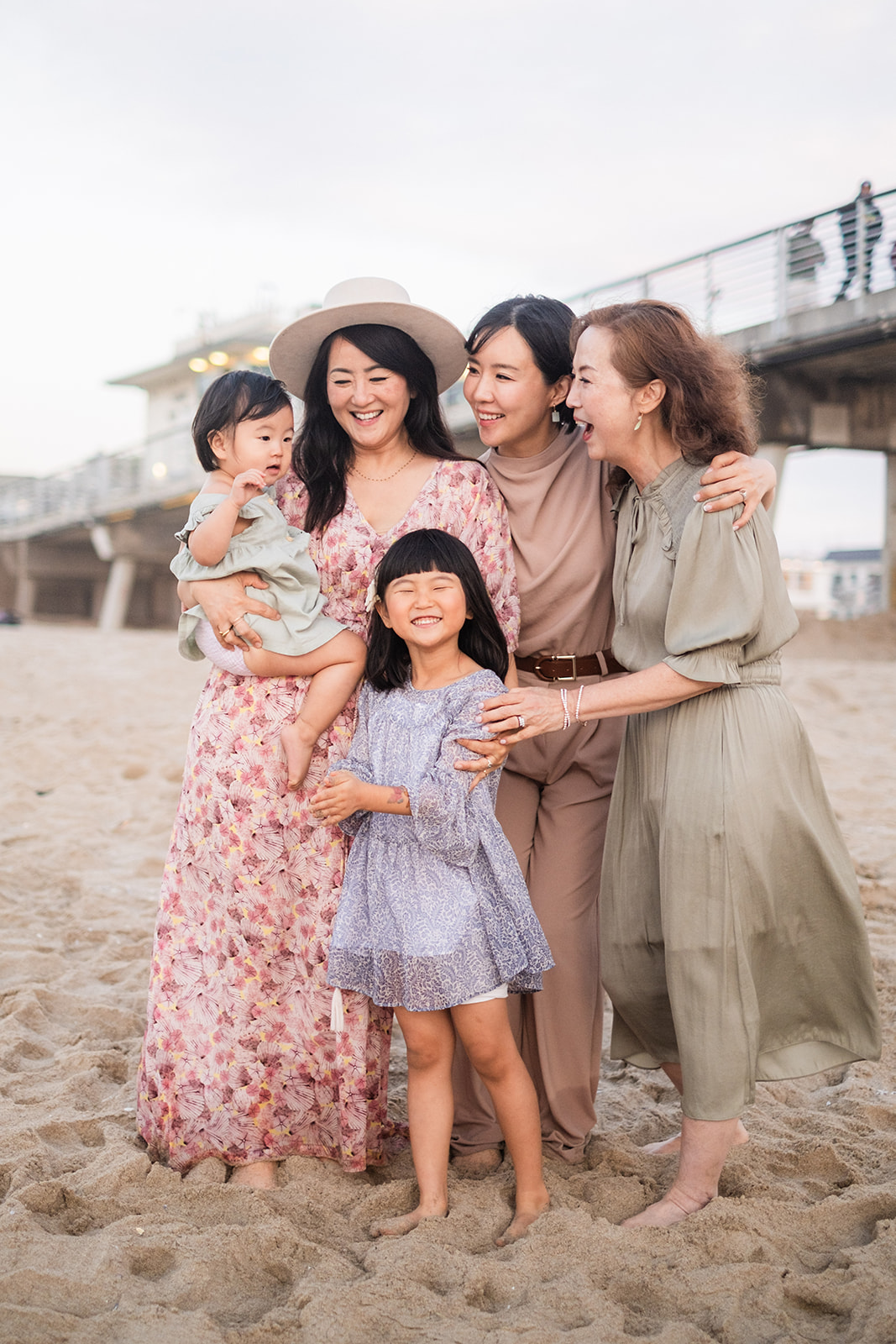 Three generations of women laughing together on the sand