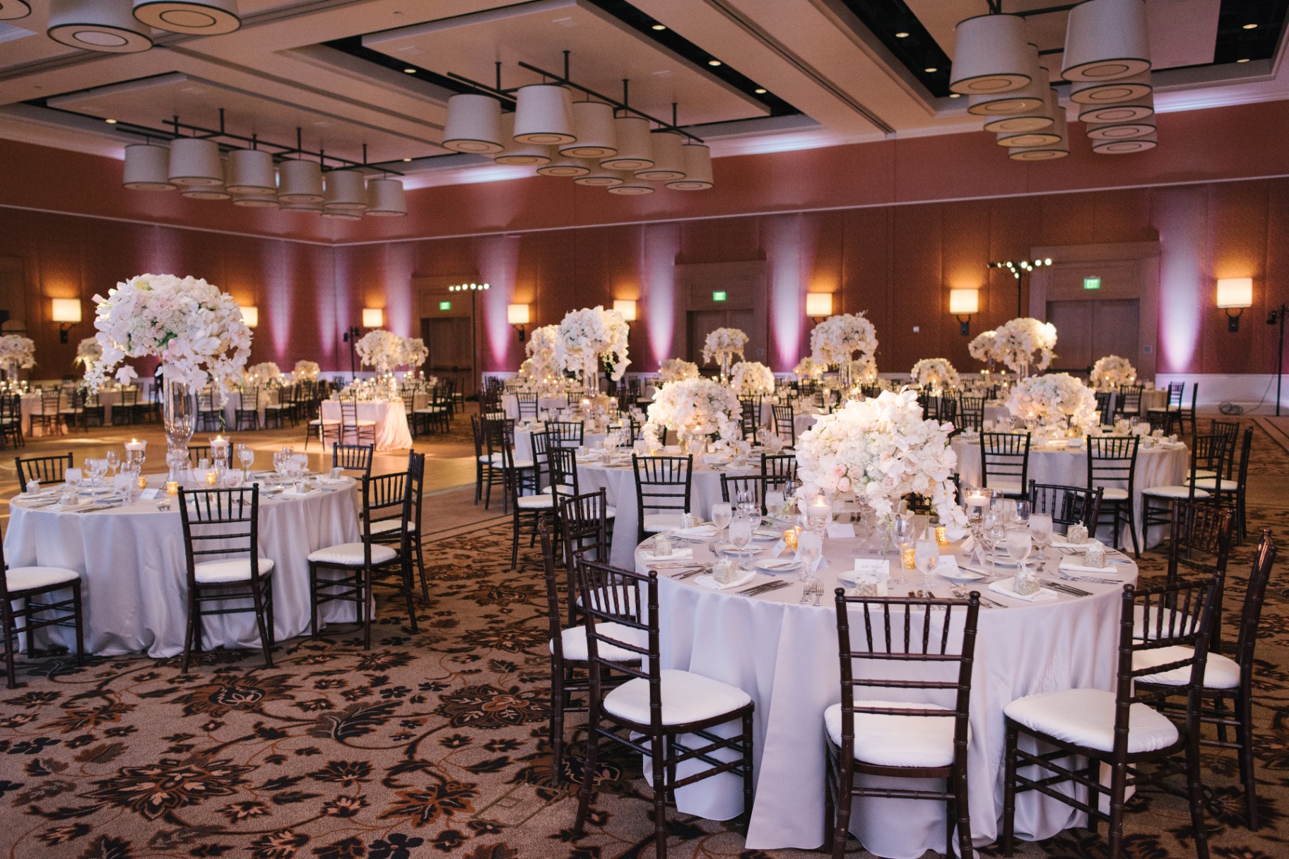 Elegant wedding reception ballroom with tall white floral centerpieces and warm uplighting at Terranea Resort in Rancho Palos Verdes, California.