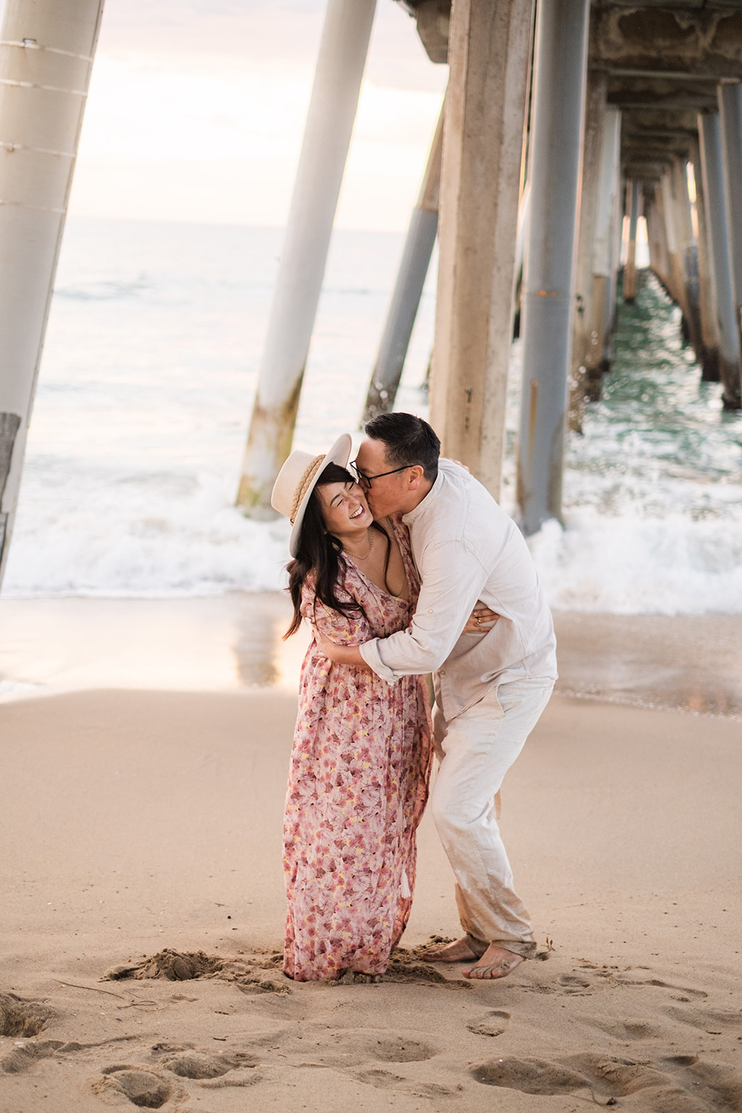 Parents laughing and kissing under the pier